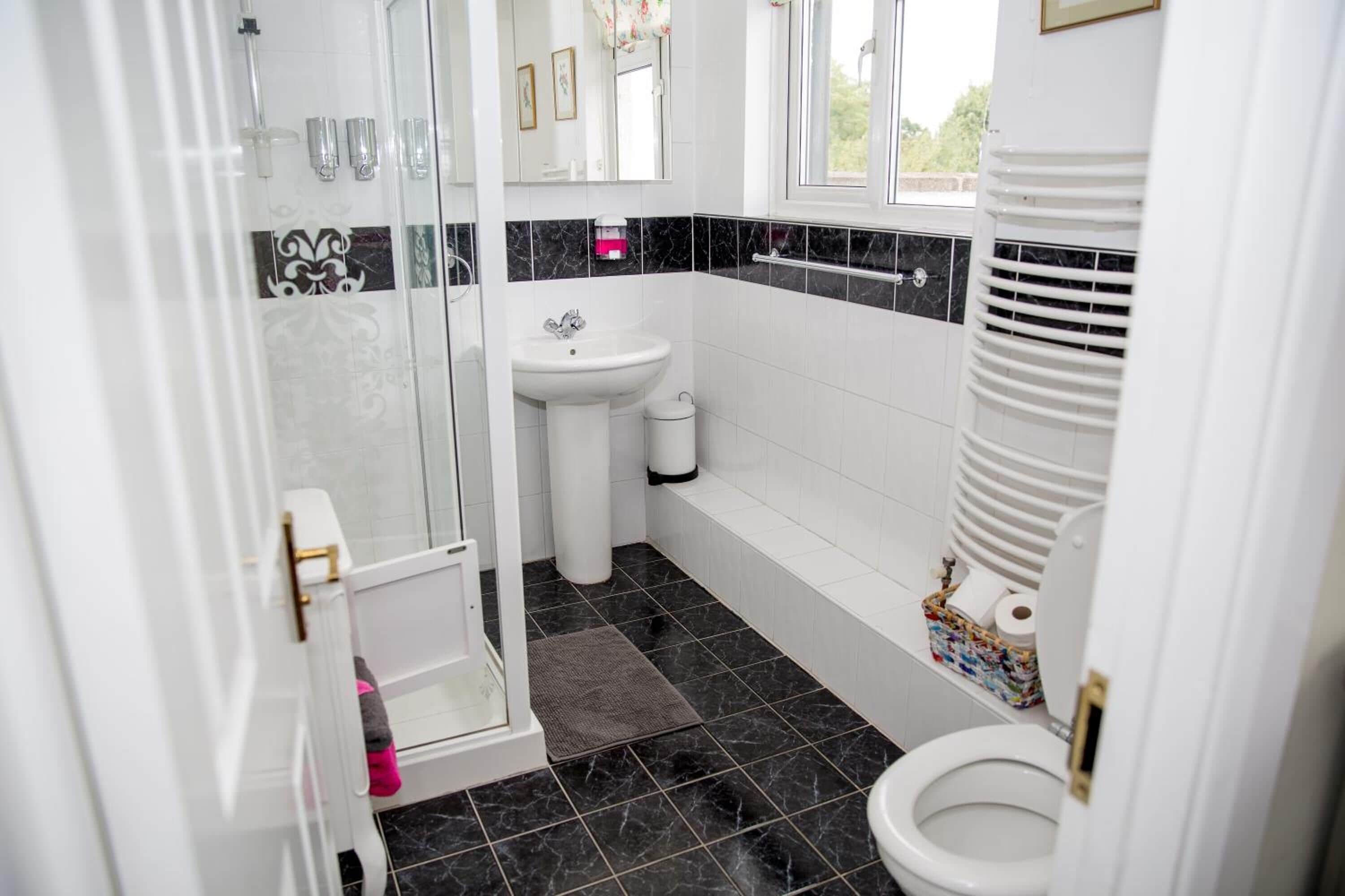 Un baño con ducha, lavamanos, inodoro y ventana.