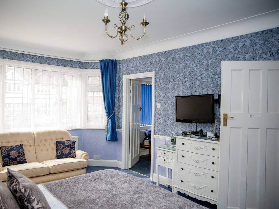 A bedroom with a large bed, a sofa, a television, and a wardrobe.