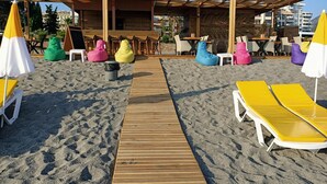 A beachside seating area with colorful bean bags and lounge chairs, a wooden deck, and a covered seating area with tables and chairs. - Bora Bora Butik Hotel (Alanya)