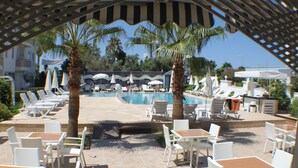 A poolside area with lounge chairs and tables, palm trees, and umbrellas. - Bora Bora Butik Hotel (Alanya)