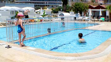 Relax by the serene pool surrounded by lounge chairs and umbrellas.