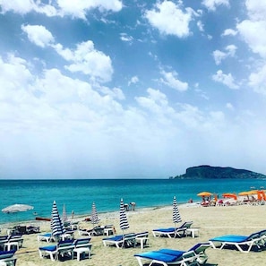 A beach with rows of sun loungers and umbrellas, a clear sky, and a calm sea. - Bora Bora Butik Hotel (Alanya)