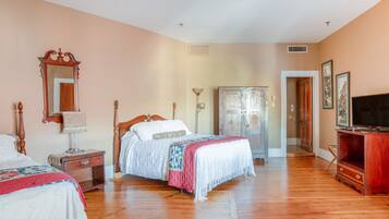 A bedroom with a wooden bed, a wardrobe, a television, and a mirror.