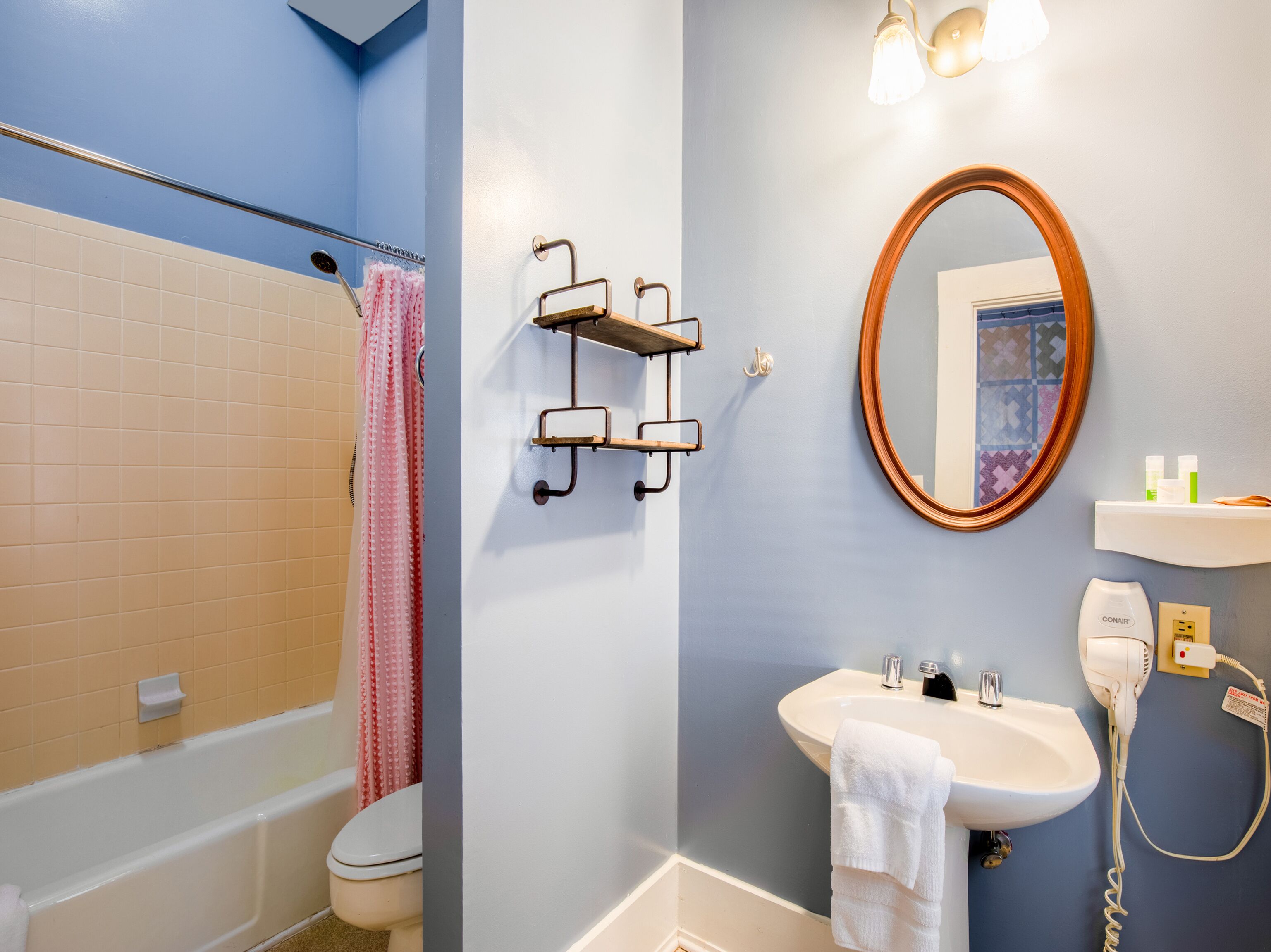 A bathroom with a bathtub, toilet, sink, and a mirror.