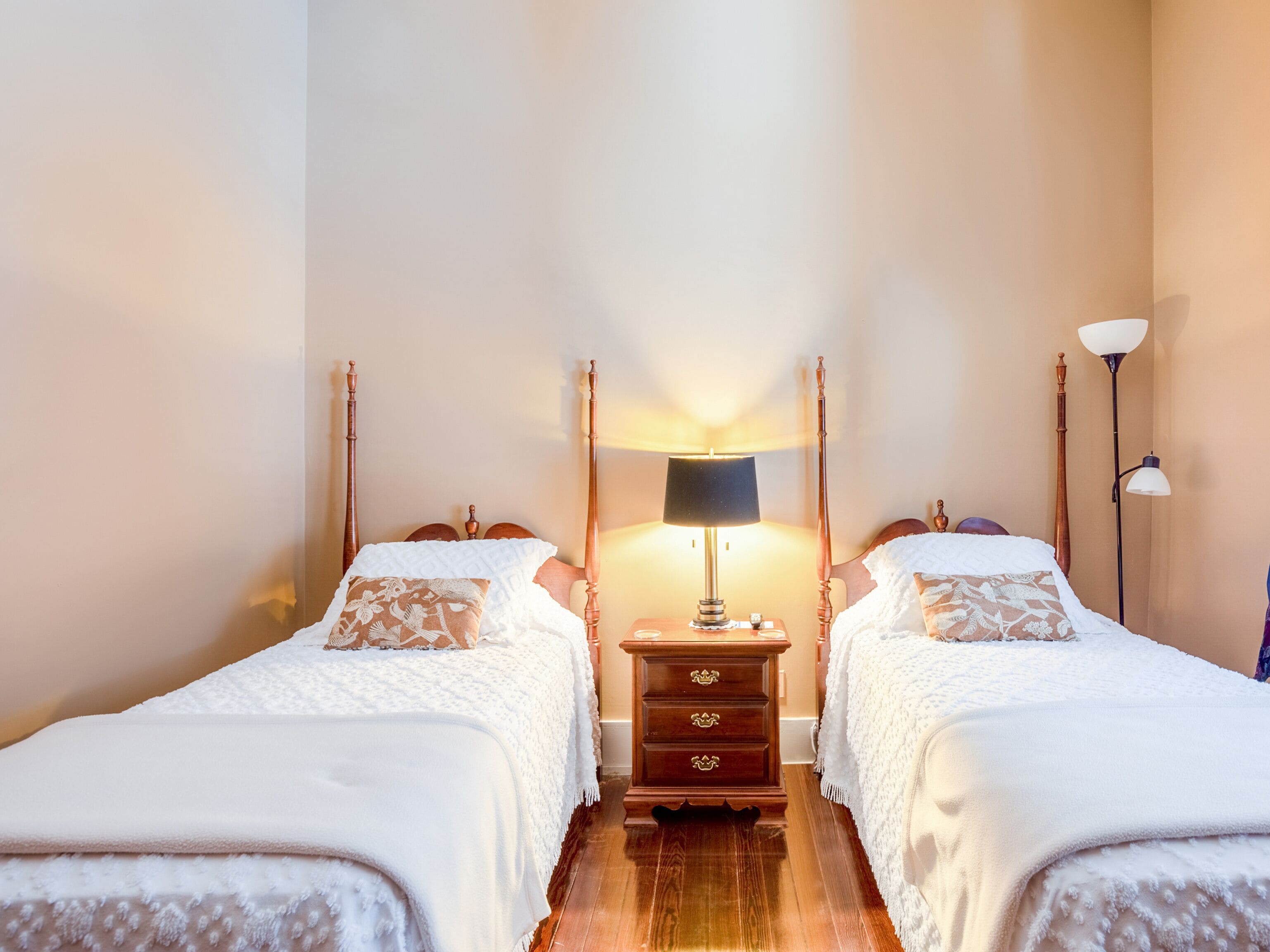 Une chambre d’hôtel avec deux lits, une table de chevet avec une lampe et une commode.