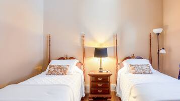 Une chambre d’hôtel avec deux lits, une table de chevet avec une lampe et une commode.