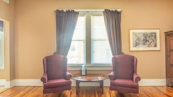 A room with two armchairs, a small round table, and a window with curtains.