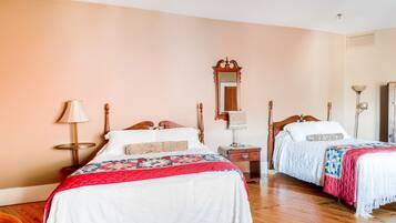A hotel room with two wooden beds, a wooden nightstand, a mirror, and a lamp.