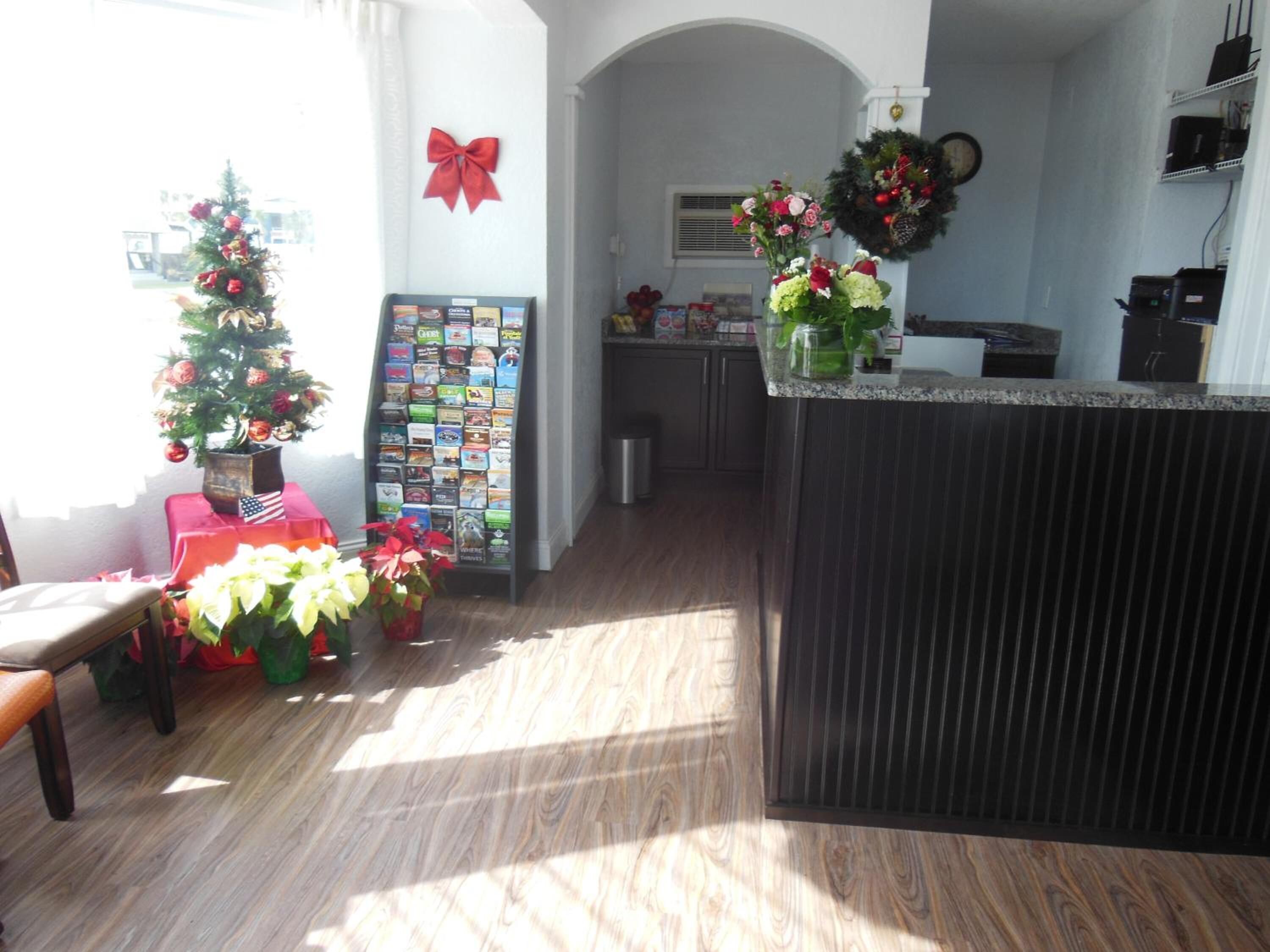 A kitchen with a wooden floor, a refrigerator, a sink, and a counter with a vase of flowers.