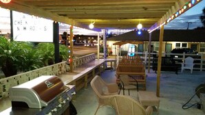An outdoor patio area with a grill, seating, and a sign advertising new rooms. - Budget Inn St. Augustine (St. Augustine)