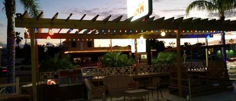 An outdoor seating area with a pergola, string lights, and a bar counter.