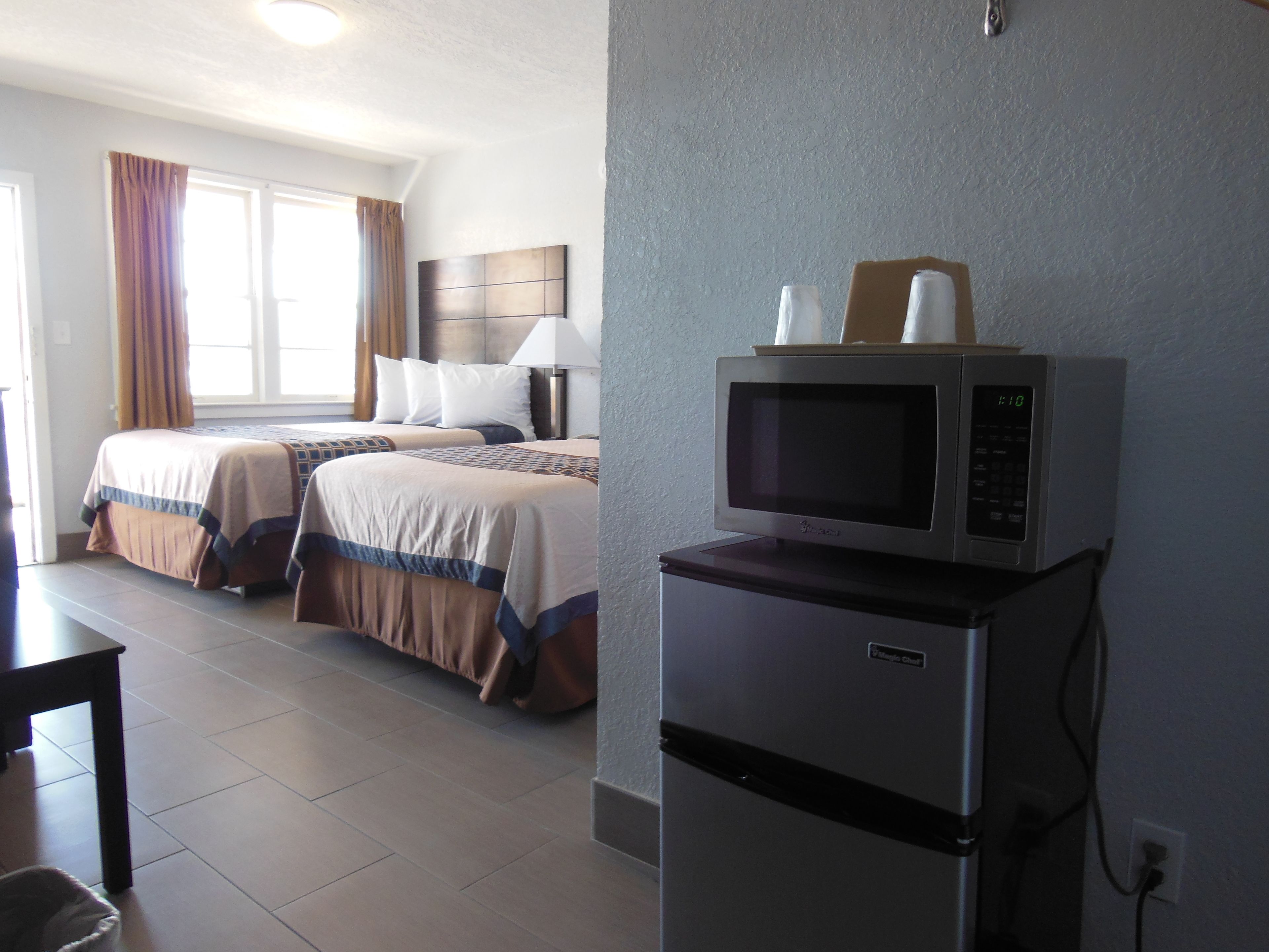 A hotel room with two beds, a microwave, and a refrigerator.
