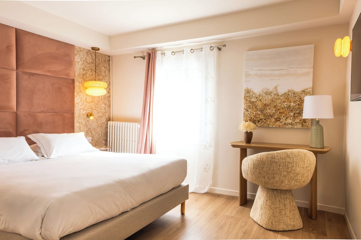 Ein Schlafzimmer mit Bett, Nachttischlampe und Blick ins Freie.