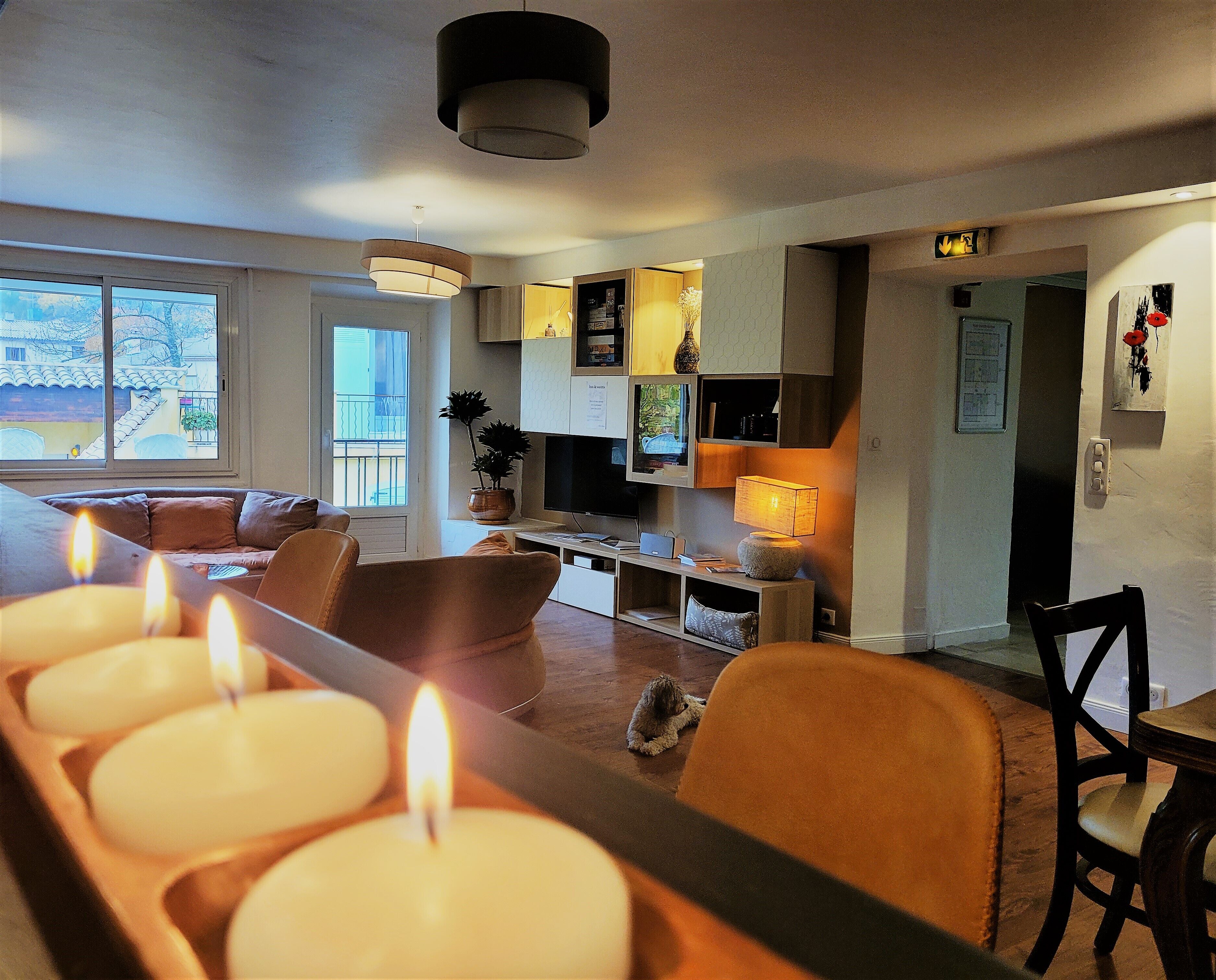 Una sala de estar moderna con un sofá, una mesa de comedor con velas, un televisor y una estantería.