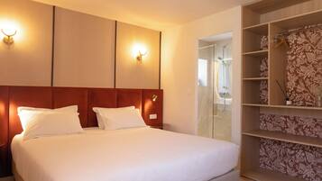 Een hotelkamer met een bed, een kledingkast en een badkamer, zichtbaar door een open deur.