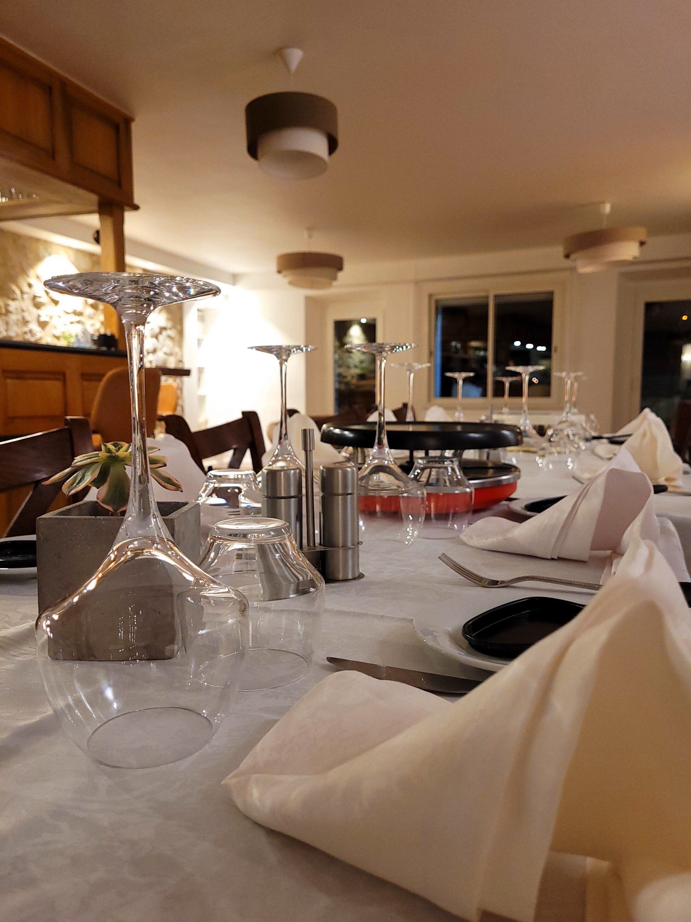 A dining table set with multiple wine glasses, a centerpiece, and silverware.