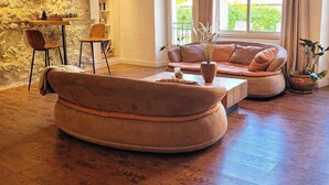 Una sala de estar con pared de piedra, mesa de centro de madera, sofá y estantería.