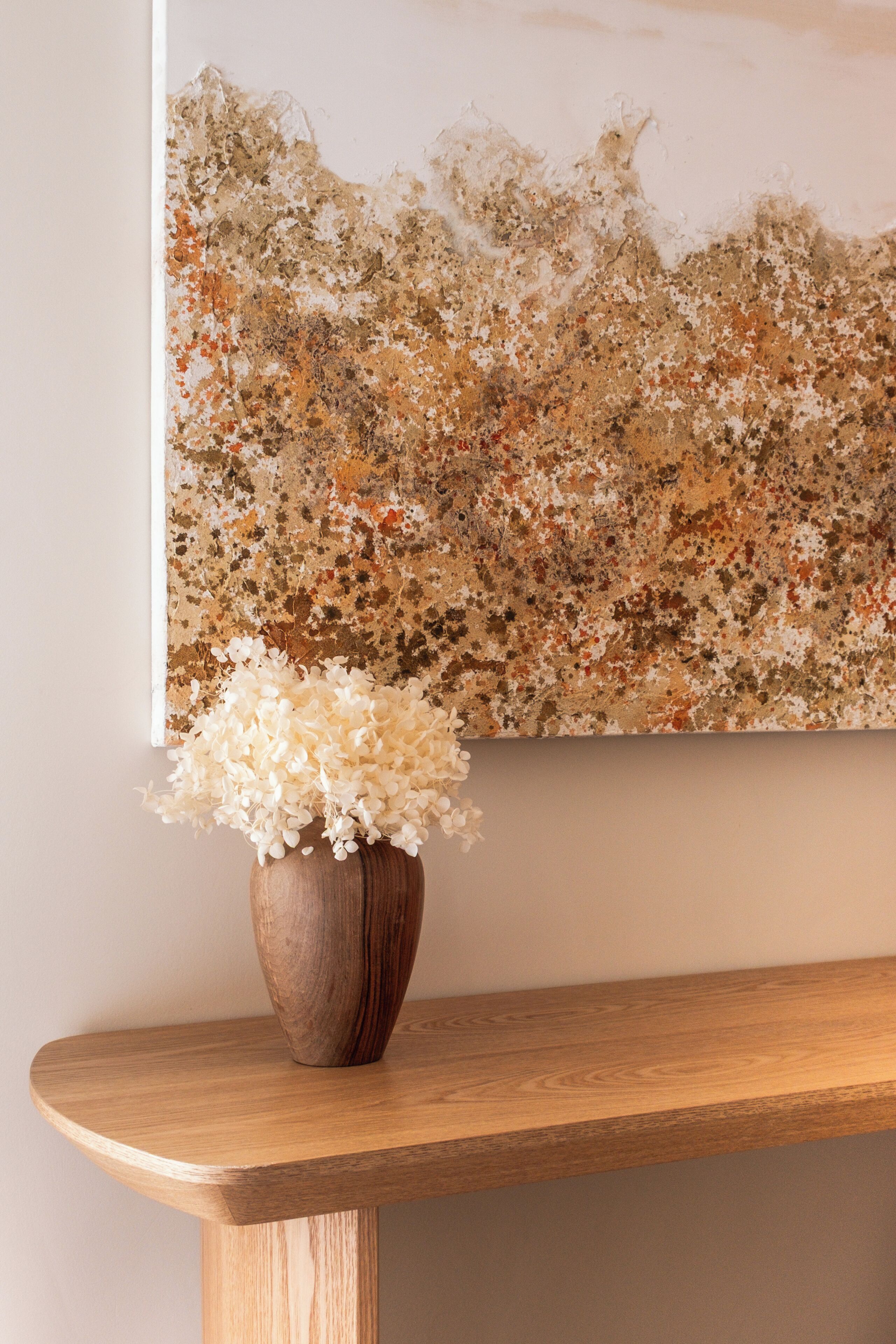 A wooden bench with a vase of white flowers.