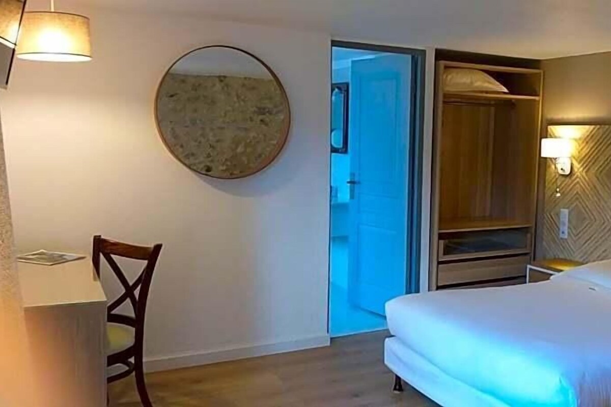 Une chambre d’hôtel comprenant un lit, une chaise, un bureau, un miroir et une armoire.