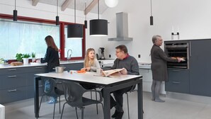 Una cocina moderna con una isla central, iluminación colgante y un horno empotrado.