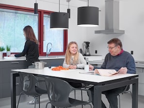 A modern kitchen with a dining table, chairs, and a person reading a book.
