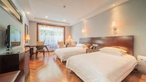 Habitación de hotel con dos camas, un escritorio, un televisor, una silla y una ventana con cortinas.