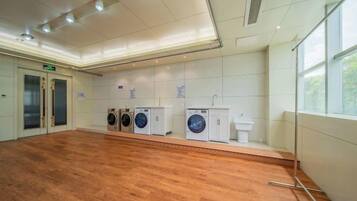 A laundry facility with multiple washing machines and dryers, a sink, and a wooden floor.