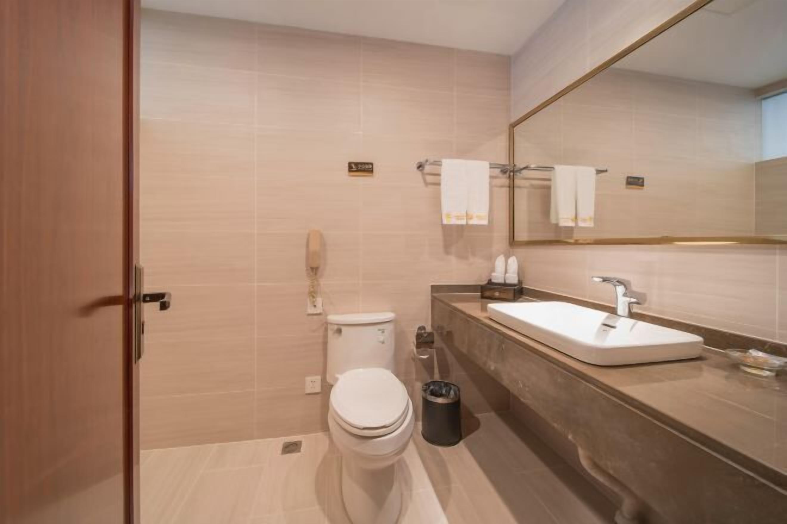A modern bathroom with a toilet, sink, and mirror.