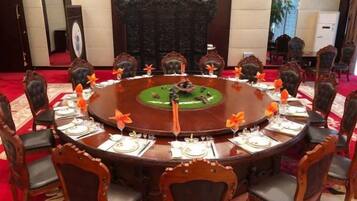 A round table with chairs, each with a plate, a glass, and a napkin.