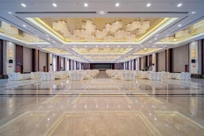 A spacious banquet hall with rows of white round tables and chairs, a polished marble floor, and a high ceiling with recessed lighting. - Anhui International Hotel (Nantong)