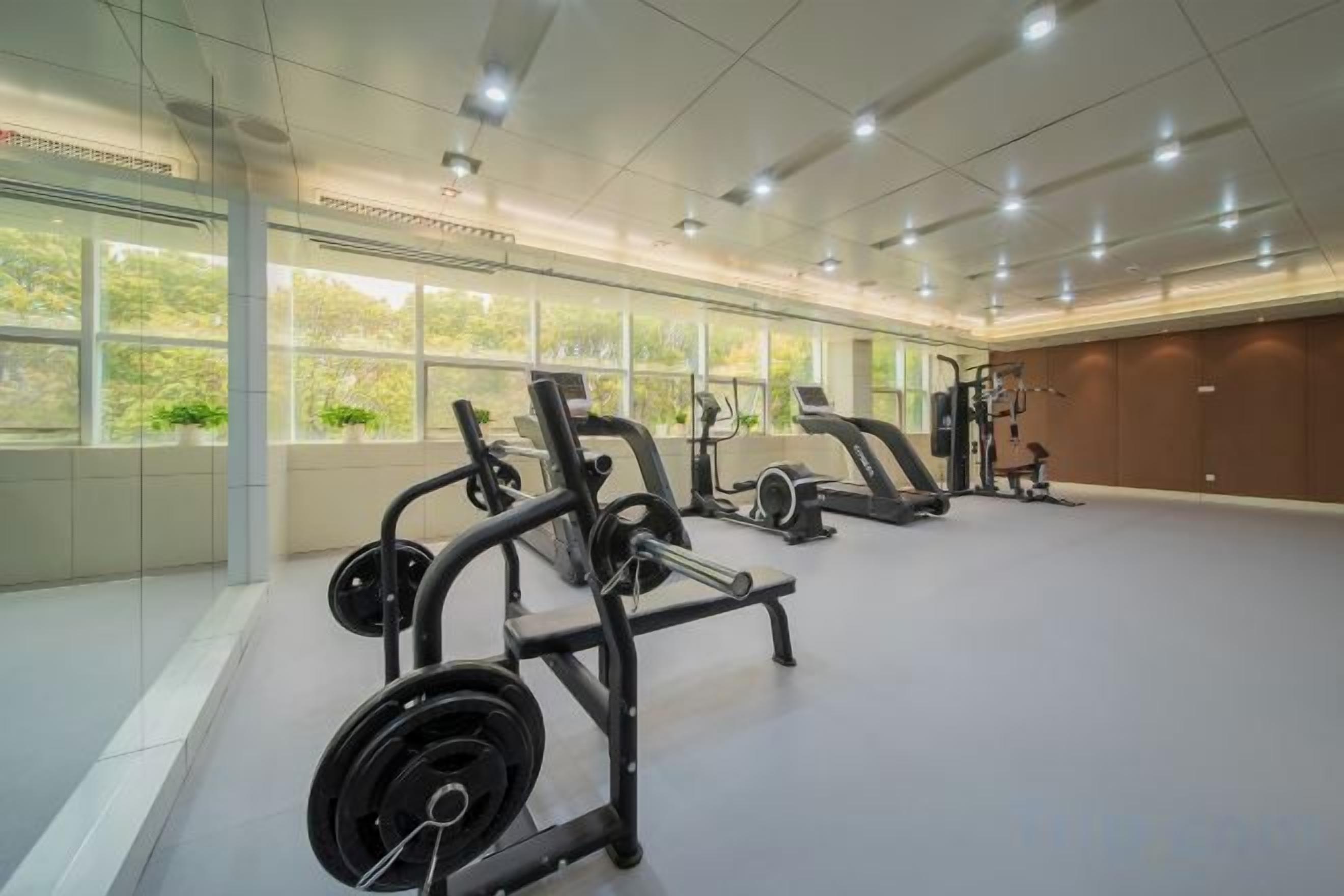Een fitnessruimte met gewichthefapparatuur, loopbanden en cardioapparaten.