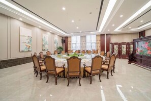 A conference room with a round table, chairs, and a television screen. - Anhui International Hotel (Nantong)