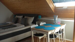 Un dormitorio tipo loft con cama, una mesa de comedor con sillas y una pequeña zona de escritorio.
