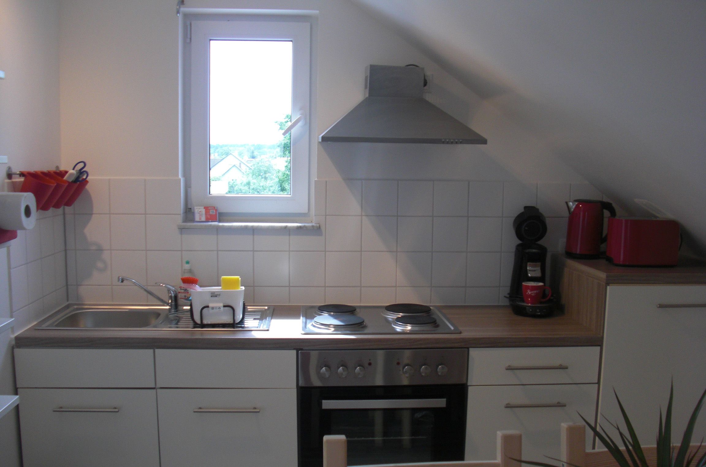 A compact kitchen with a window, a stove, an oven, and a sink.