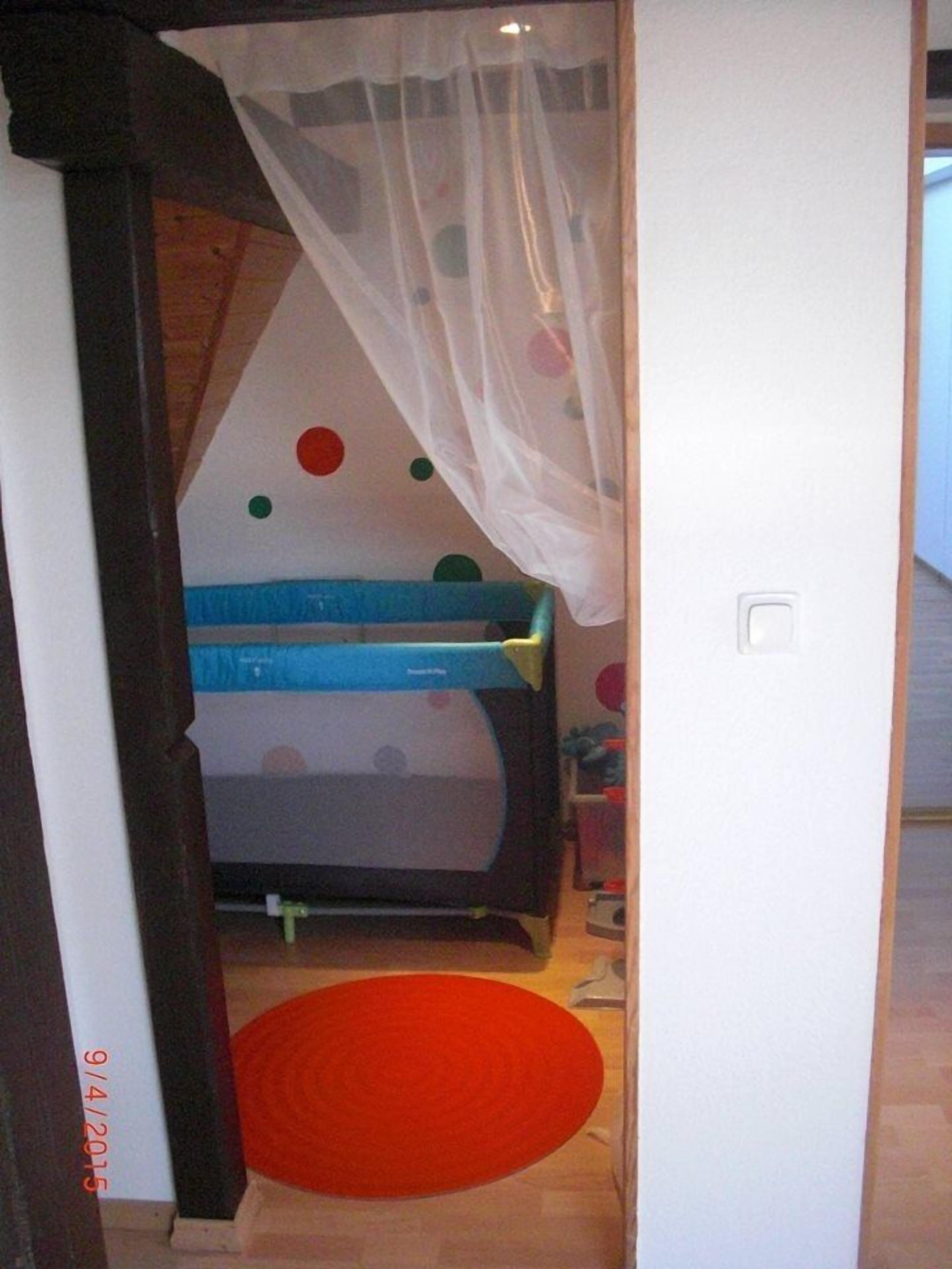 Un dormitorio infantil con una cama litera, una pared de lunares y una alfombra roja.