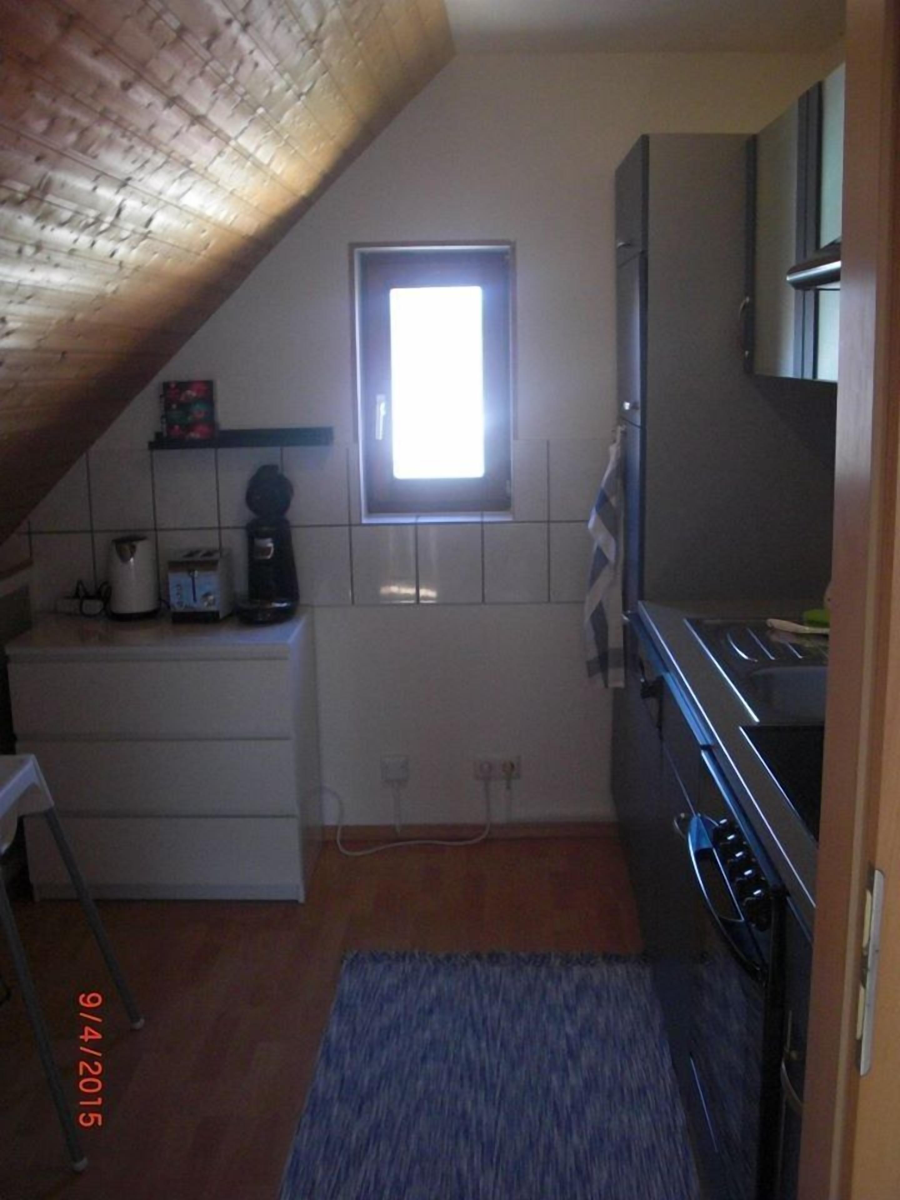 A small kitchen with a window, a stove, and a sink.