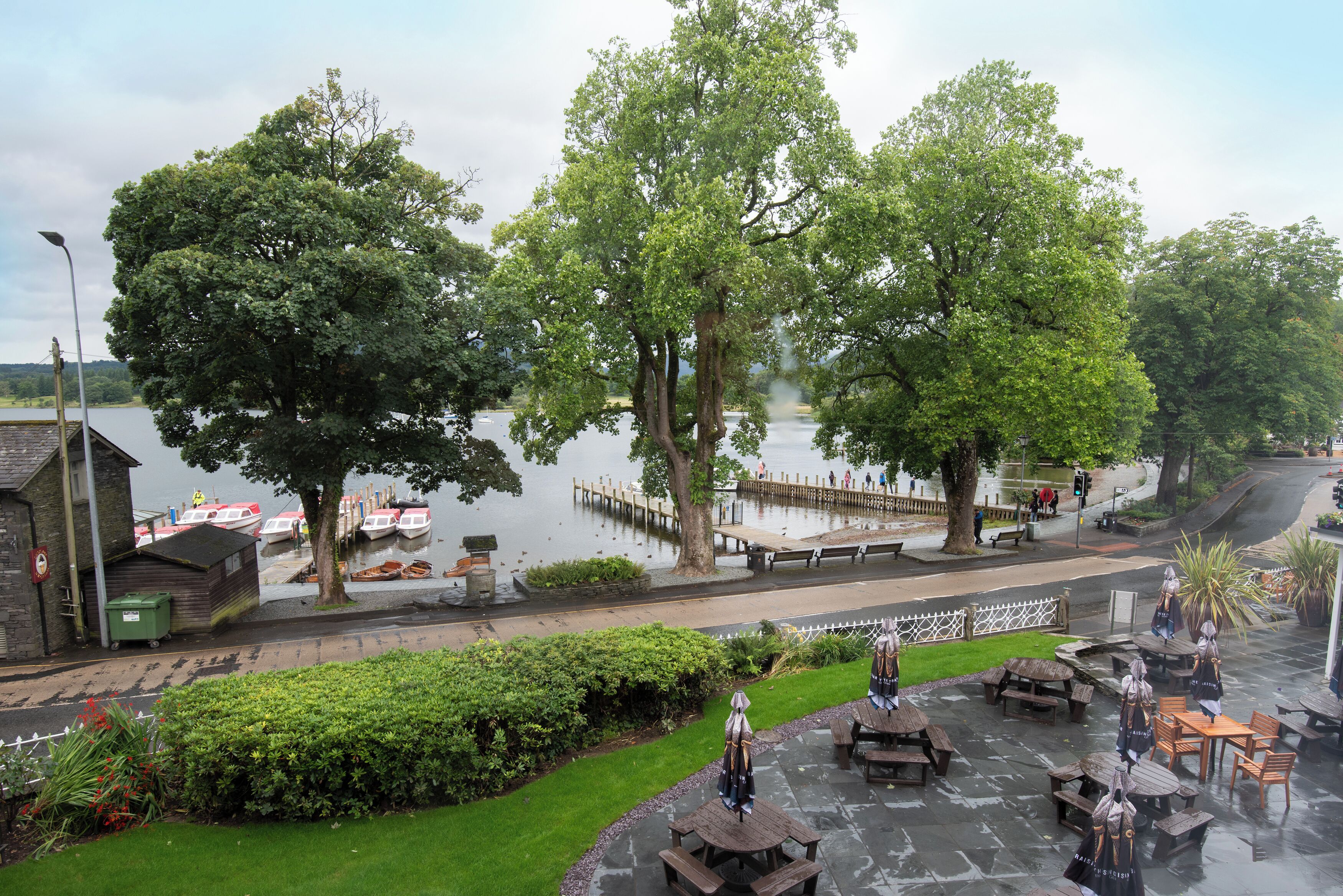 A riverside park with picnic tables, benches, and a dock with boats.