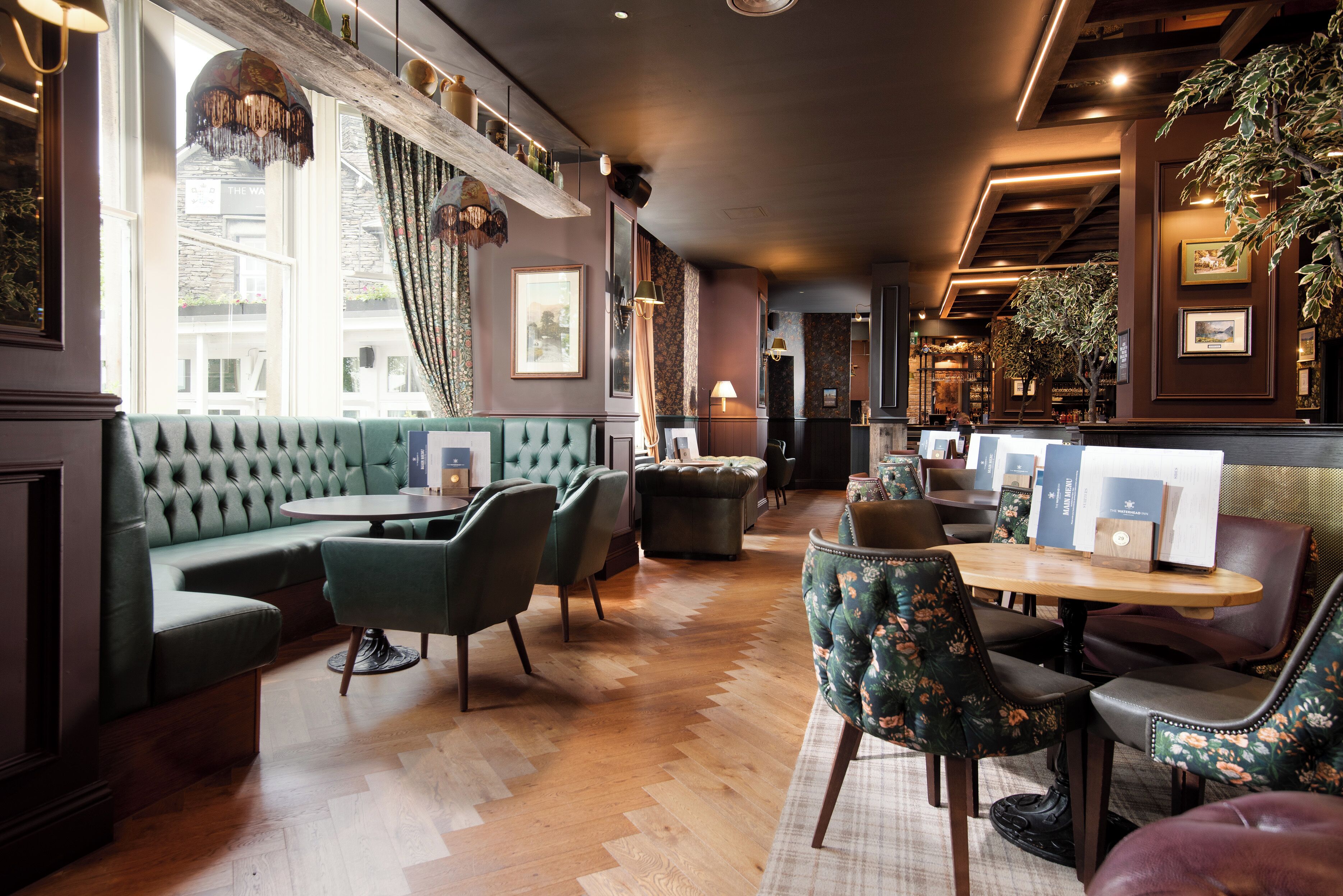 A cozy lounge area with a green sofa, wooden tables, and chairs.