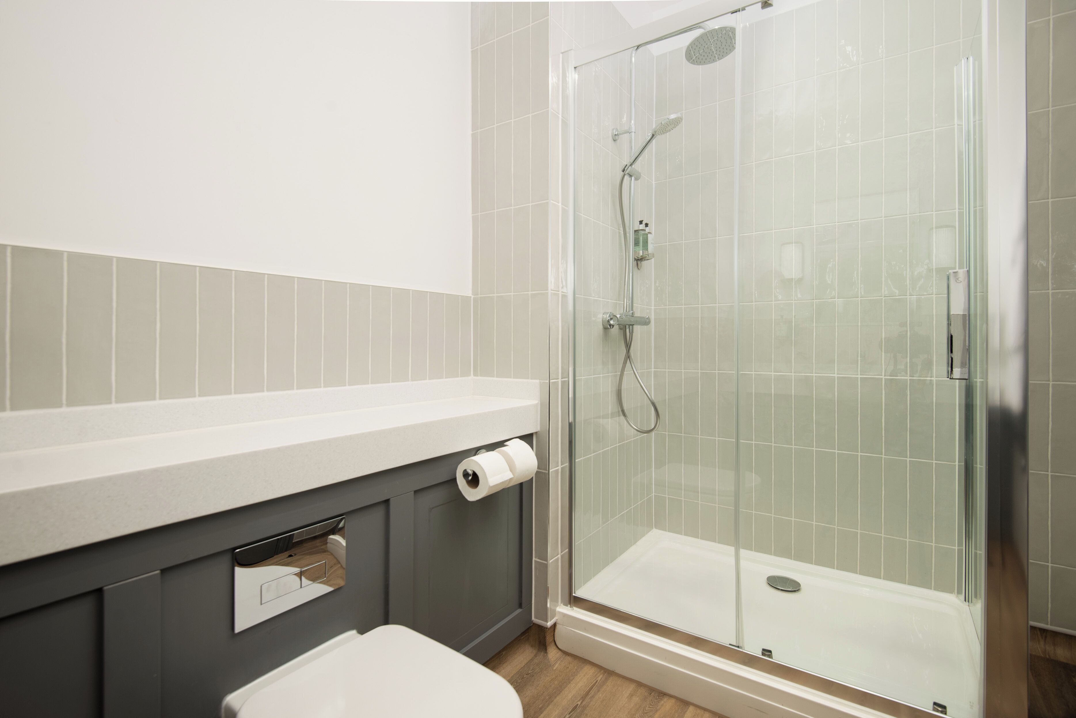 A modern bathroom with a glass shower enclosure, a toilet, and a sink with a towel rack.