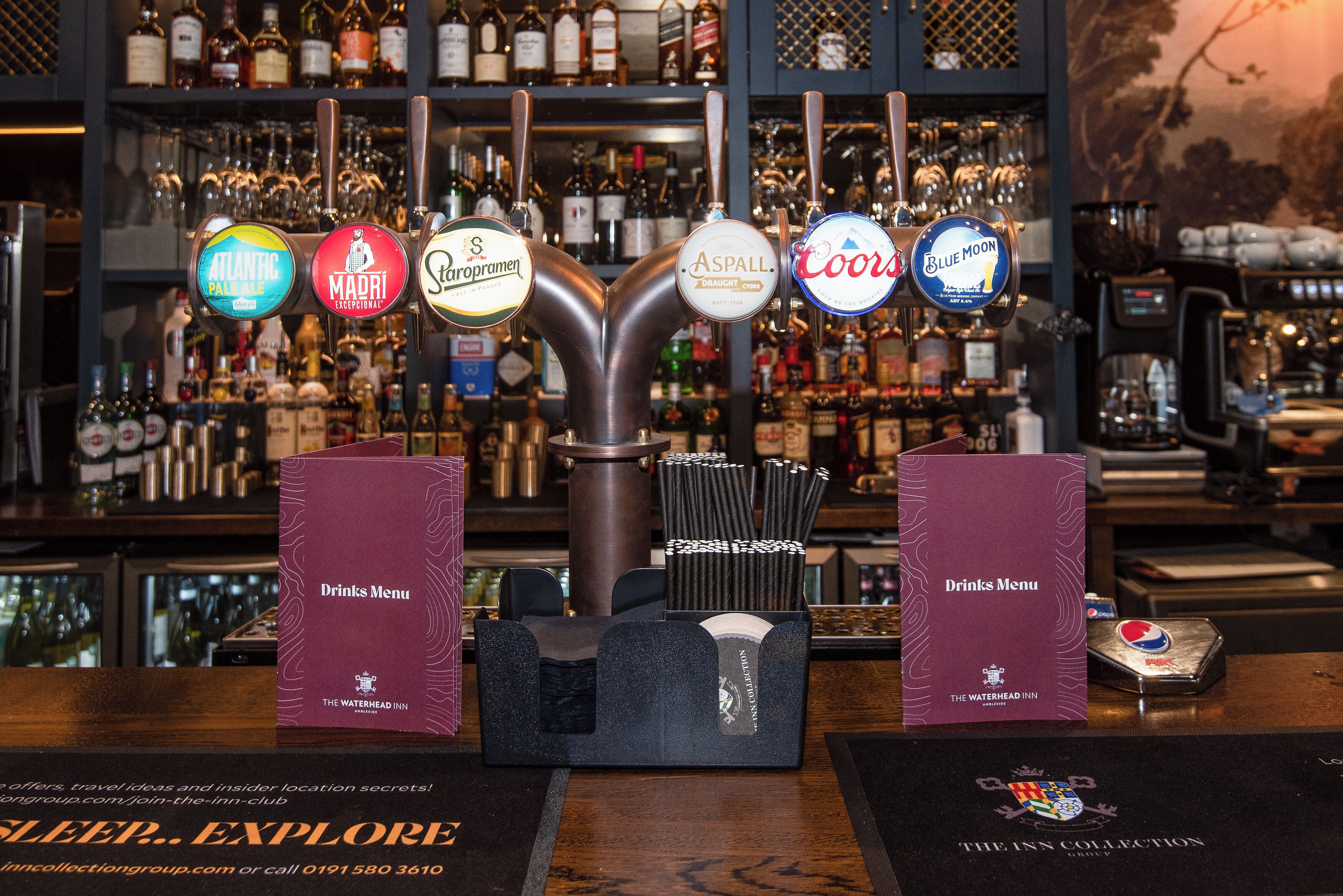 A bar area with multiple beer taps, a drinks menu, and a water bottle.