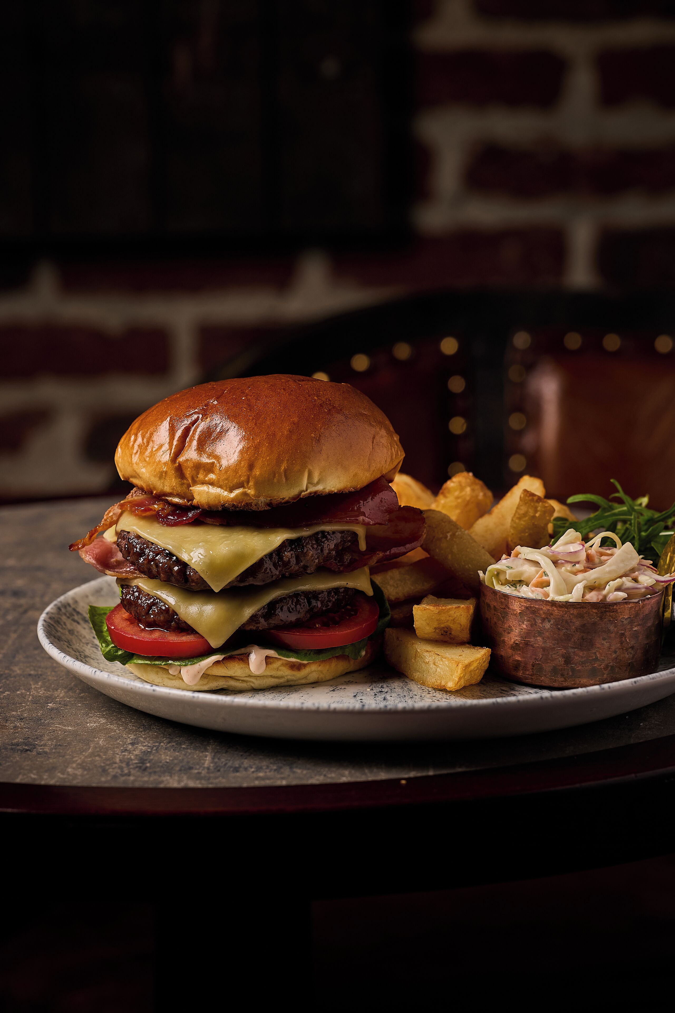 A burger with fries and coleslaw on a plate.