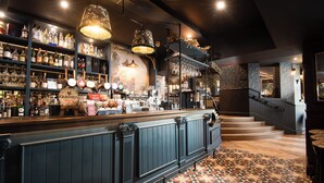 A bar area with shelves of liquor bottles, a bar counter, and a patterned floor. - The Waterhead Inn - The Inn Collection group (Ambleside)