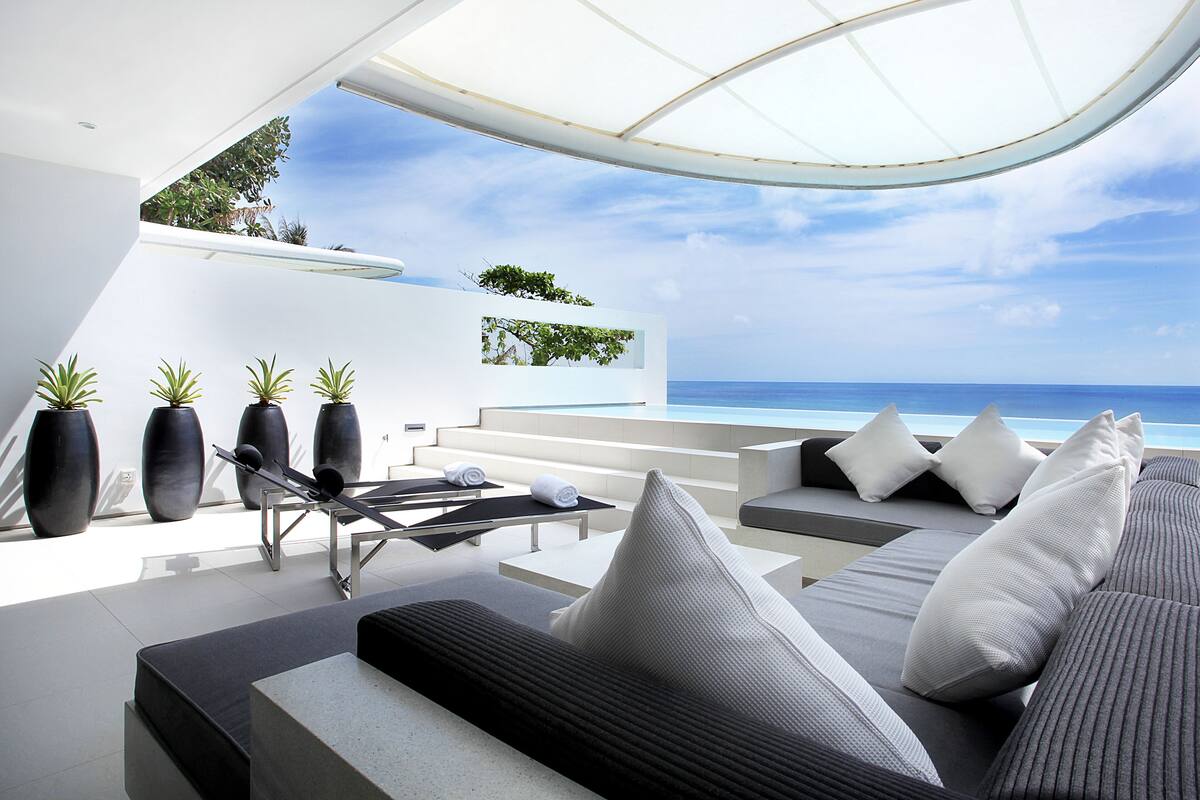 A modern outdoor lounge area with a pool, seating, and potted plants.