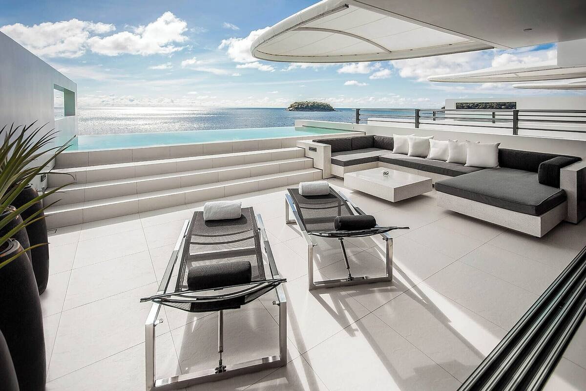 A modern outdoor lounge area with a pool, a sofa set, and a sunbed.