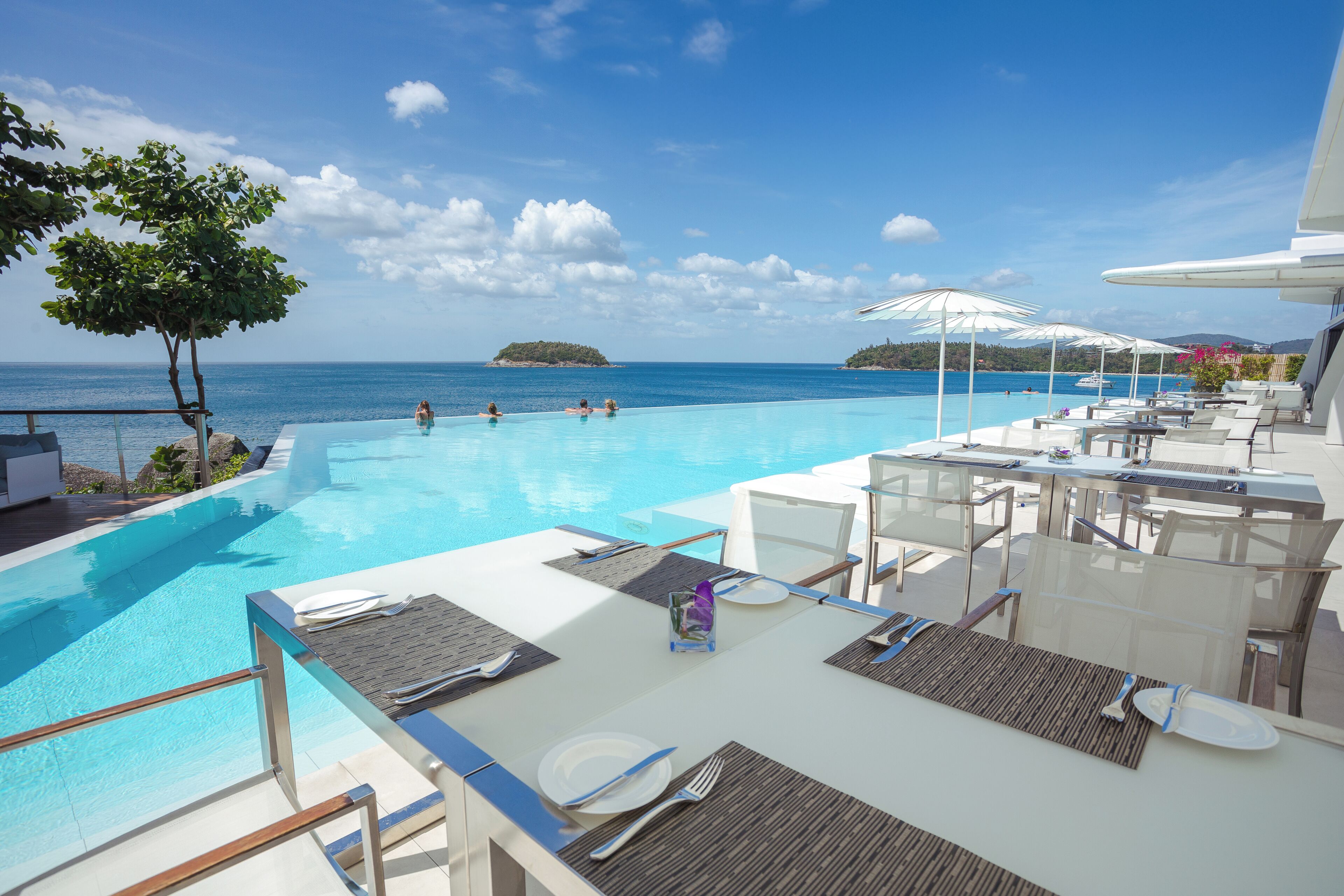 Zona junto a la piscina con sillones de descanso, una mesa de comedor y vista al océano.