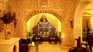Una habitación acogedora con pared de piedra, un ventanal con cortinas amarillas, un sofá y una mesita de café.
