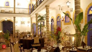 Comedor con mesas dispuestas para una comida, con un arreglo floral central y velas.