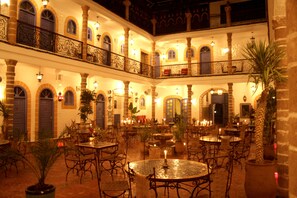 A courtyard with multiple tables and chairs, a fountain, and potted plants. - Hotel Villa Damonte (Essaouira)
