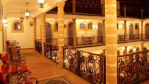 Un vestíbulo de hotel con barandales decorados, columnas y arcos.