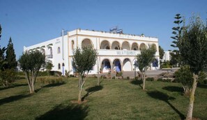 A white building with the name "Villa Damonte" and "Hotel Villa Damonte" on the facade, featuring a central arched entrance and multiple balconies. - Hotel Villa Damonte (Essaouira)